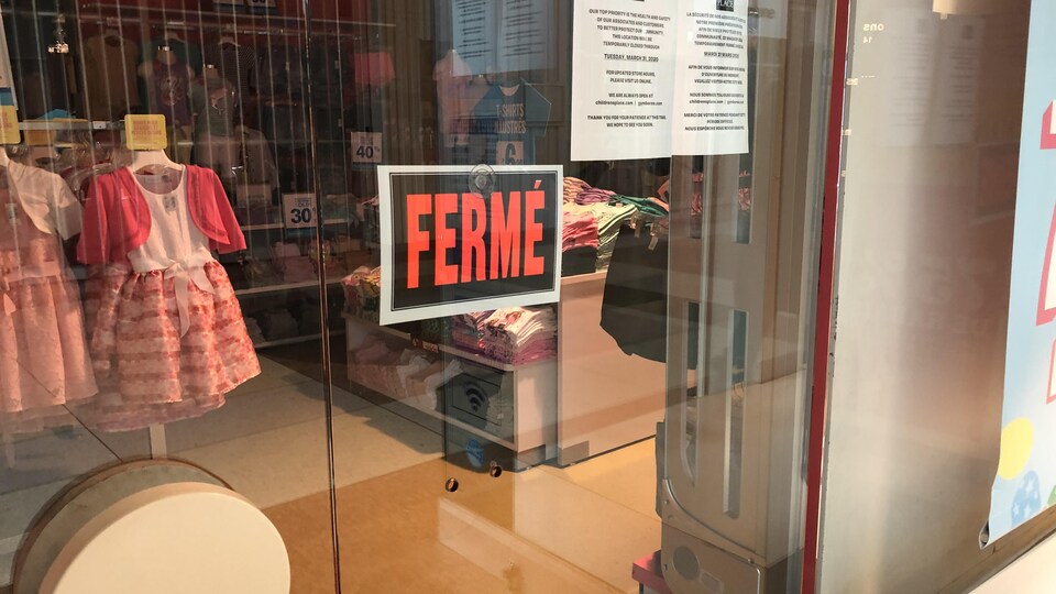 Une vitrine de magasin avec une pancarte «fermé».
