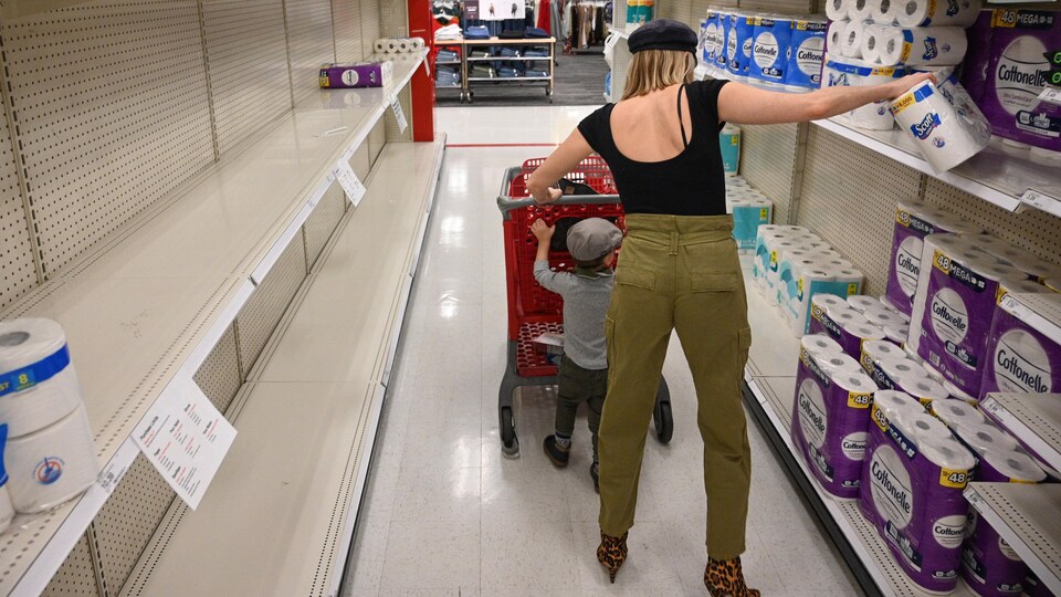 A woman walks the aisles of a department store with her child.