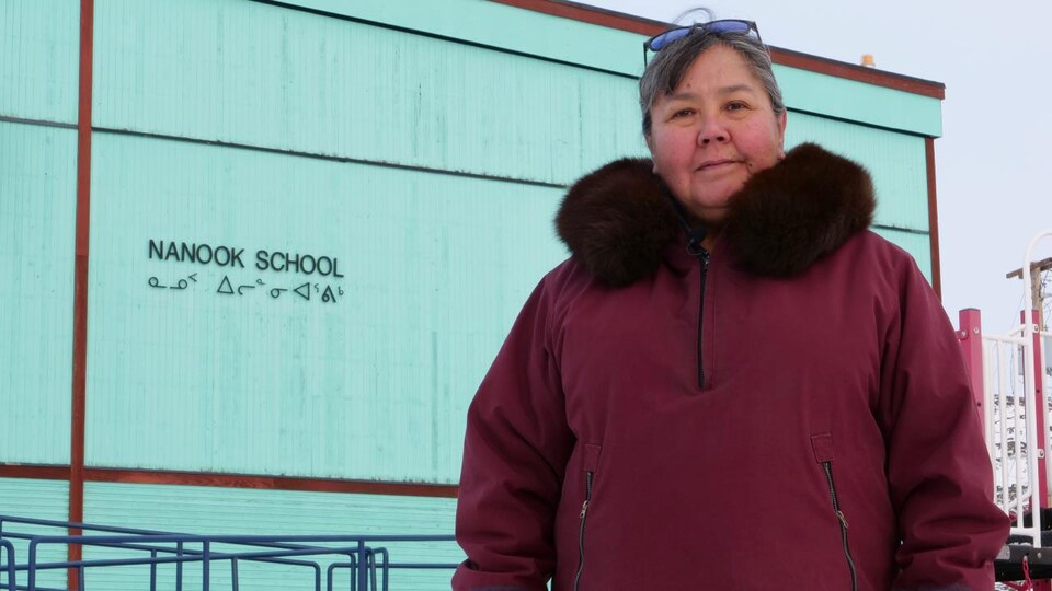 Une femme se tient debout devant une école.