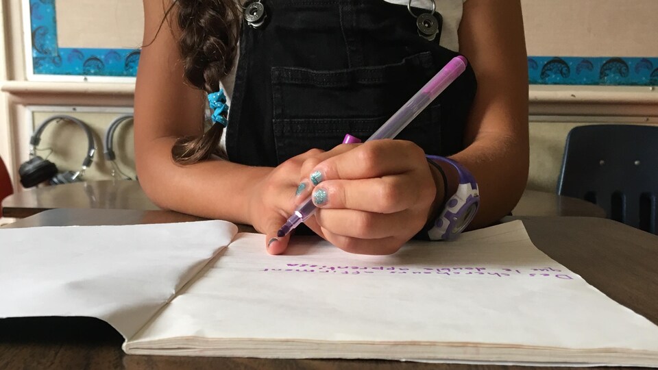 Une écolière inconnue écrit à la main dans un cahier.