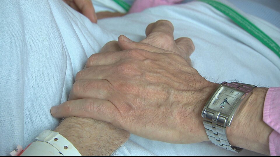 Main d'une personne âgée sur la main d'un patient à l'hôpital.