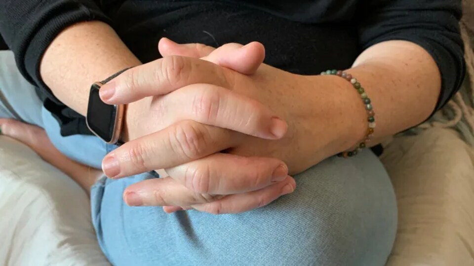 gros plan sur les mains croiser déposer sur les genou de la mère assice mais on ne vois qu'une partie de sa jambe et son ventre