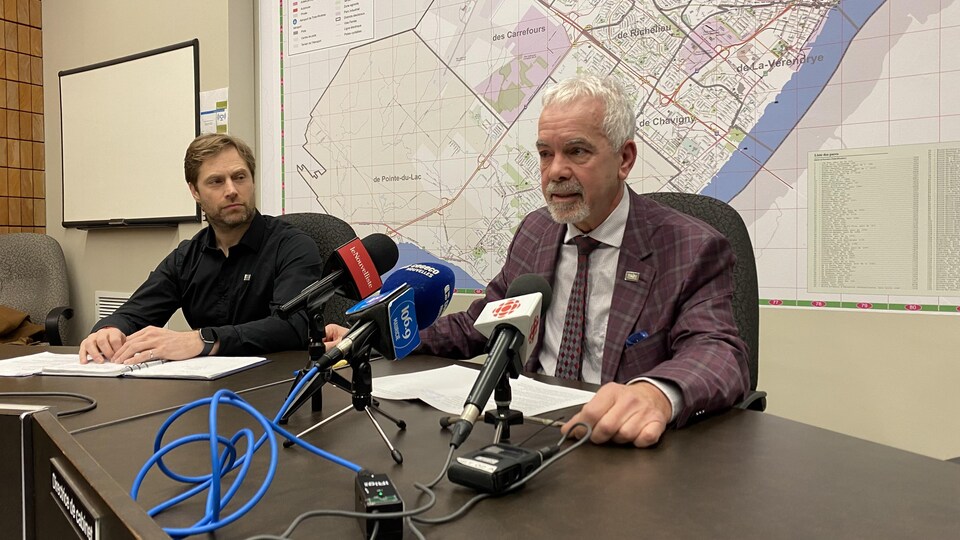 Daniel Cournoyer, à droite, et Éric Angers, à gauche, assis à une table dans l'hôtel de ville.