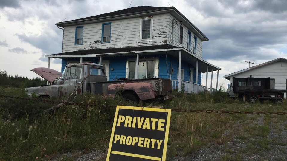 Une maison abandonnée avec un vieux camion en avant.