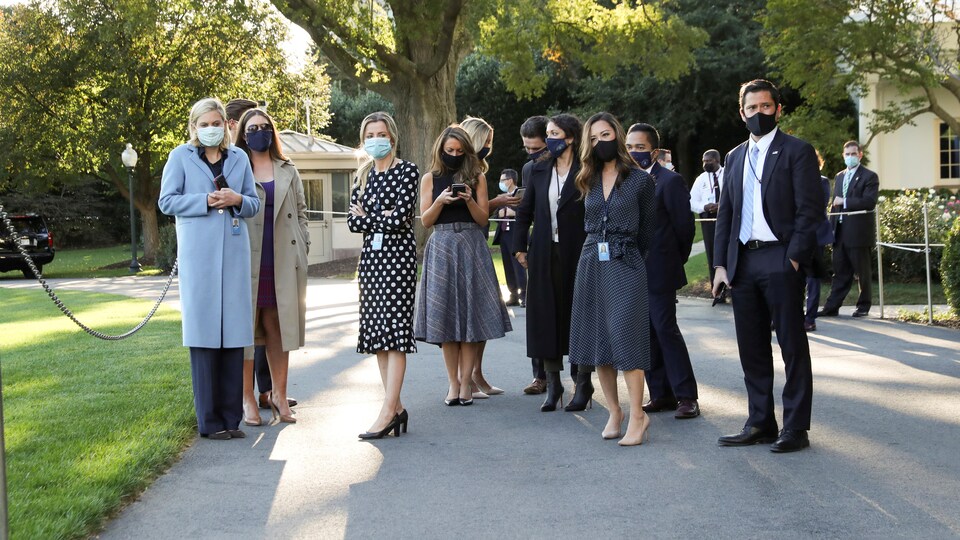 Une dizaine de personnes rassemblées à l'extérieur de la Maison-Blanche portent un masque.