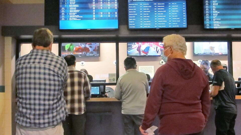 Des hommes font la file pour parier sur des événements sportifs dans une maison de jeu.