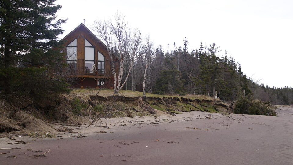 Une maison construite sur le bord de l'eau, à Pointe-Lebel : le terrain est grugé par l'eau (érosion des berges).