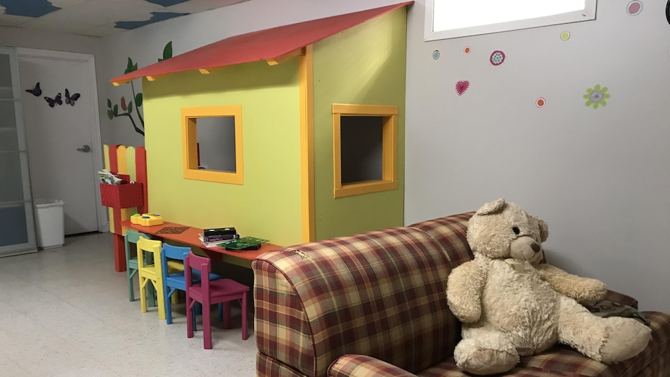 Une salle de jeux avec un toutou, une cabane et une table pour enfants.