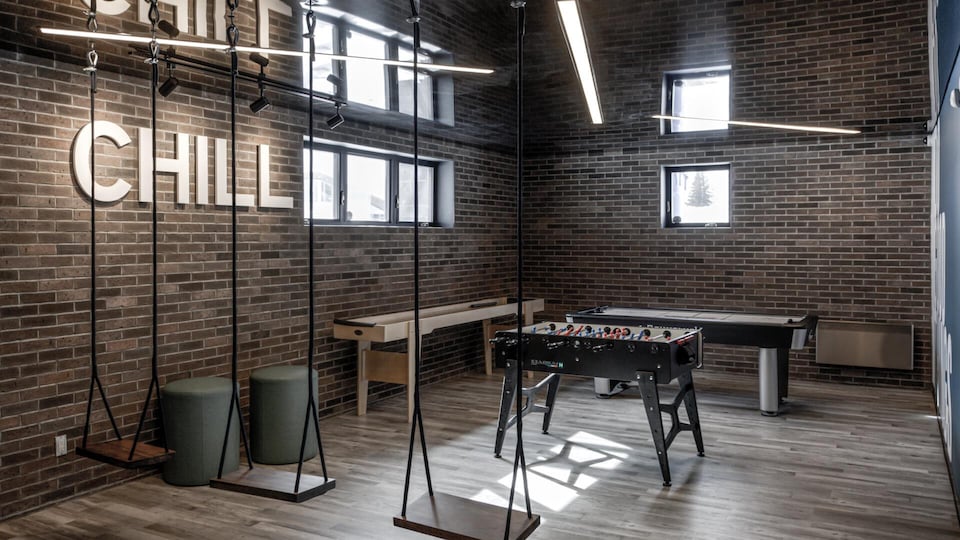Une salle avec trois balançoires et une table de baby foot.