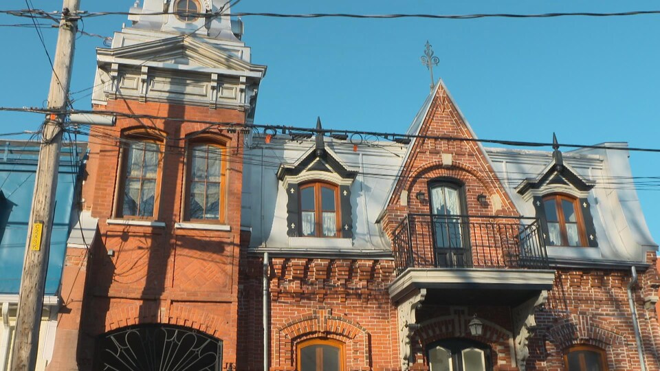 La façade d'une maison avec de petits galeries au 2e étage et des lucarnes.