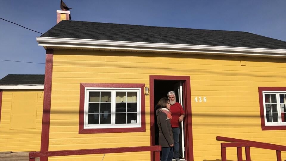 Deux personnes devant une maison jaune.