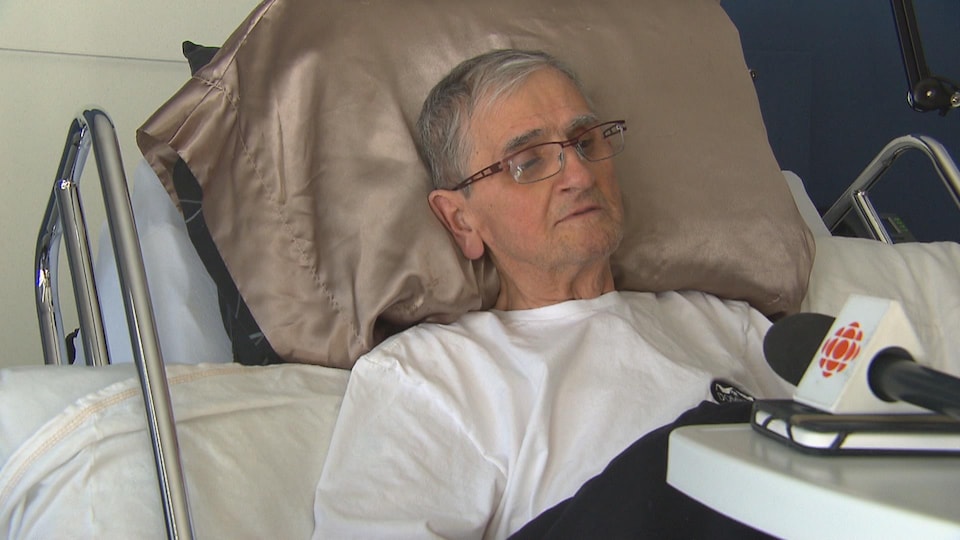Michel Dufour accordant une entrevue,. allongé sur un lit dans la chambre d'une maison de soins palliatifs. 