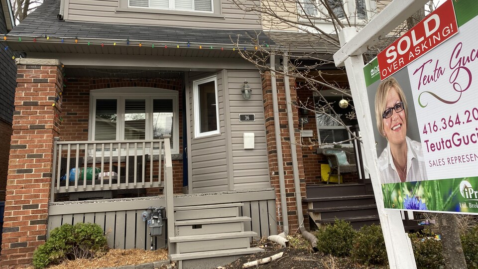 Une affiche disant « vendue au-dessus du prix demandé » devant une maison à Toronto.