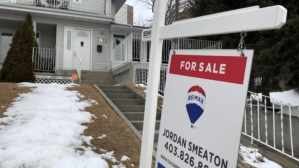 Un panneau avec l'inscription à vendre devant une maison.
