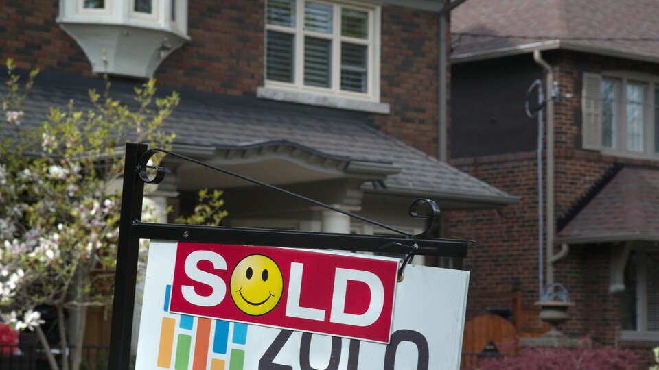 Une affiche où il est écrit « Vendu » devant une maison à Toronto.
