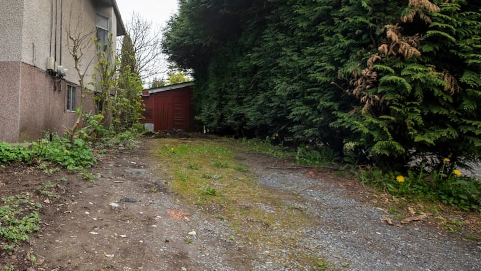 Le petit terrain à vendre est entouré d'une maison et de buissons.