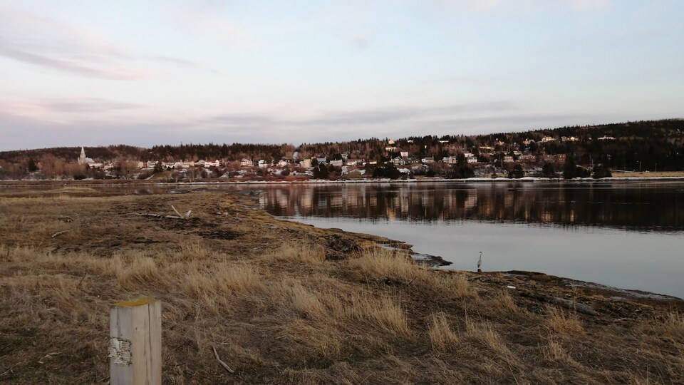 Vue sur des rangées de maisons dispersées sur une petite colline, en bordure du fleuve.