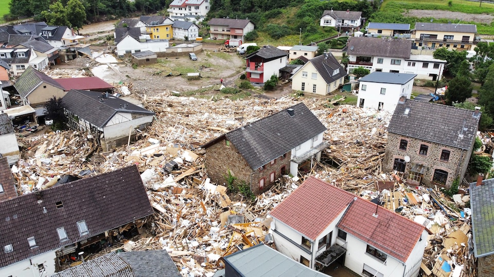 Des montagnes de débris jonchent les rues entre des maisons endommagées.