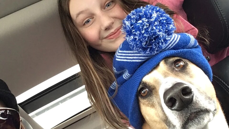 Makenna et son chien Willy qui porte un bonnet bleu, tous les deux dans une voiture.
