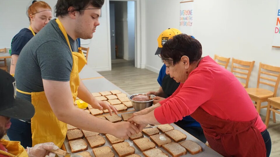 Des bénévoles font des sandwichs qui sont destinés à un organisme de charité. 