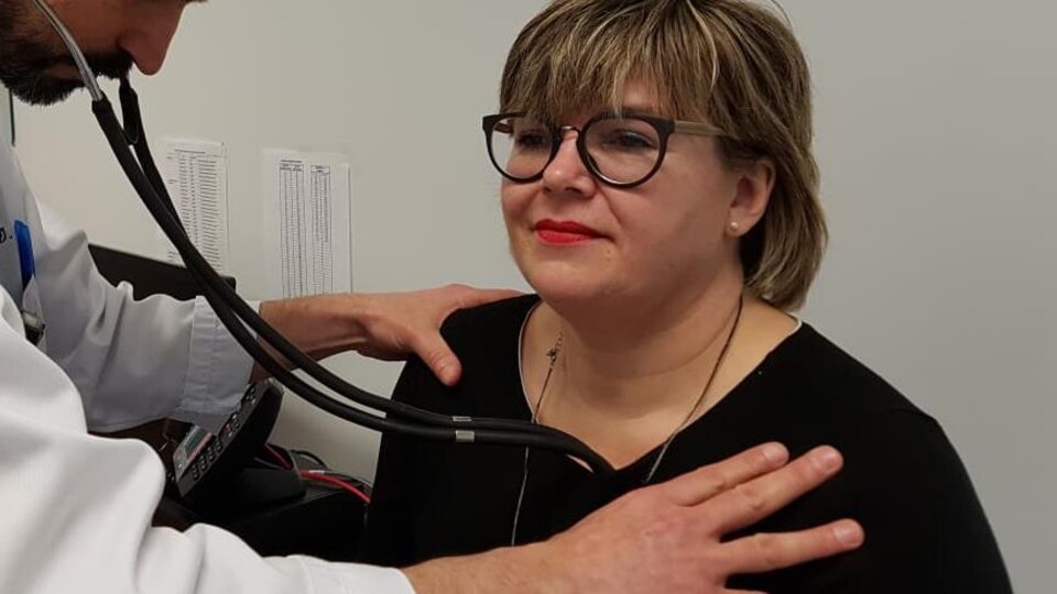 Un médecin écoute le battement de cœur d'une patiente grâce à son stéthoscope.