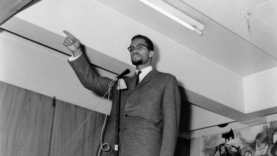 Malcom X prononce un discours debout.