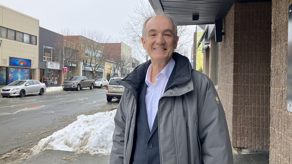 Pierre-Paul Malenfant, vêtu d'un manteau, sur le côté de la rue au centre-ville de Rouyn-Noranda.