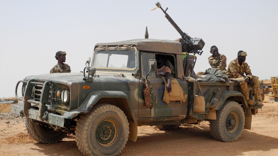 Quatre soldats près d'un camion-mitrailleuse de l'armée 