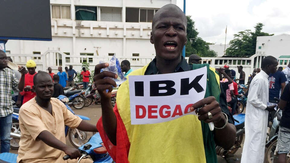 Un manifestant portant une pancarte sur laquelle est inscrit : DBK dégage (en référence au président malien)