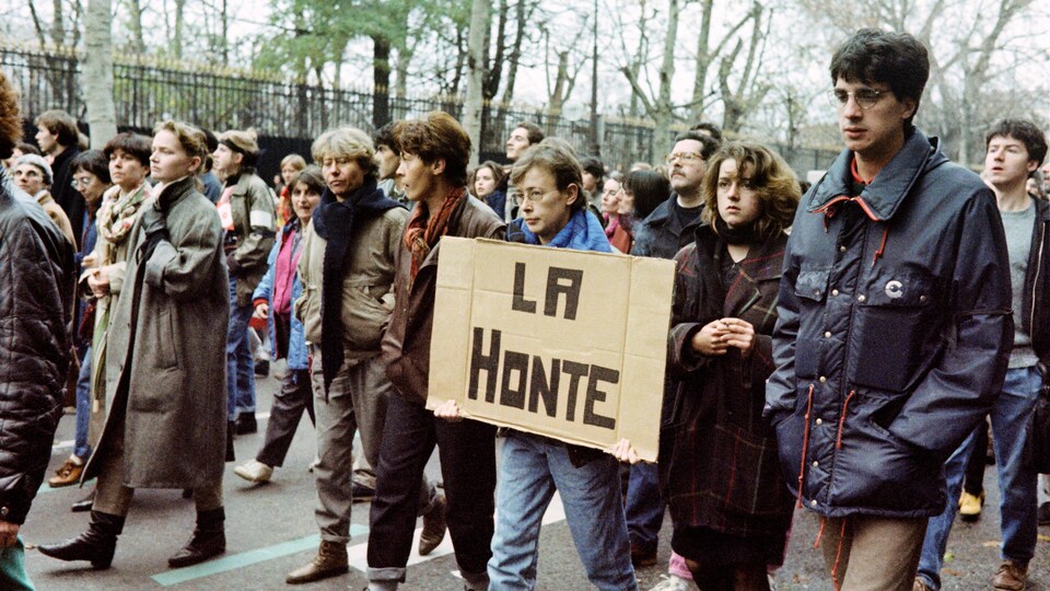 A woman holds a placard reading 'shame' at a protest in Paris in 1986.
