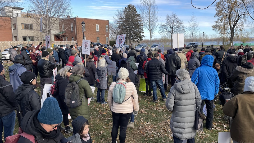 Des citoyens réunis dans un parc devant le fleuve.