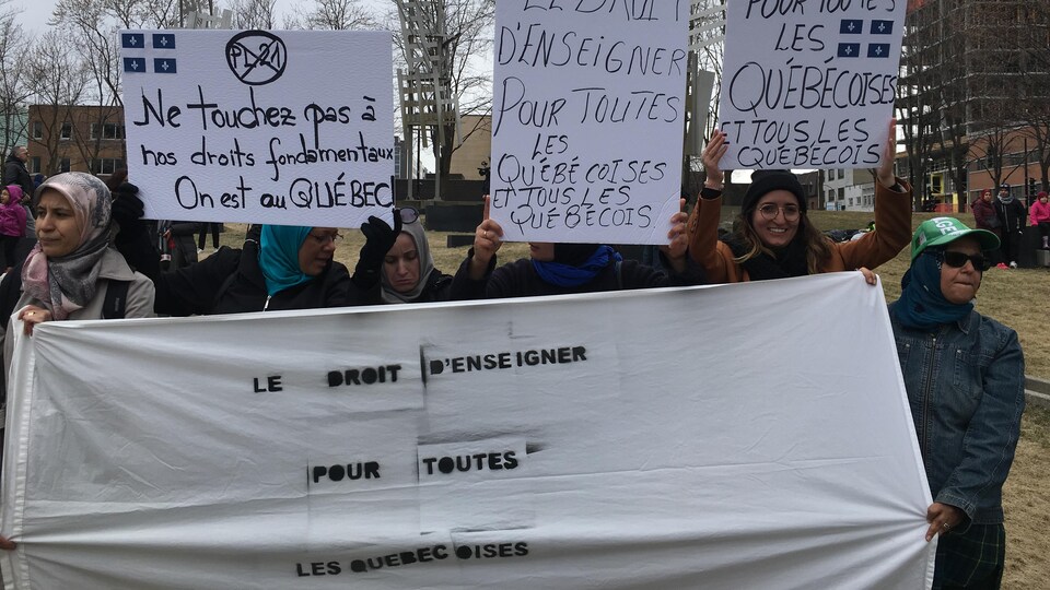 Des femmes brandissent une banderole contre la loi 21 à la place Émilie-Gamelin.