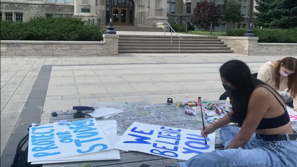 Une femme peint sur des pancartes les mots : «On te croit».