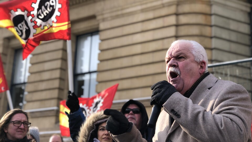 Chris Aylward parle au microphone lors d'une manifestation dehors en hiver à Ottawa.