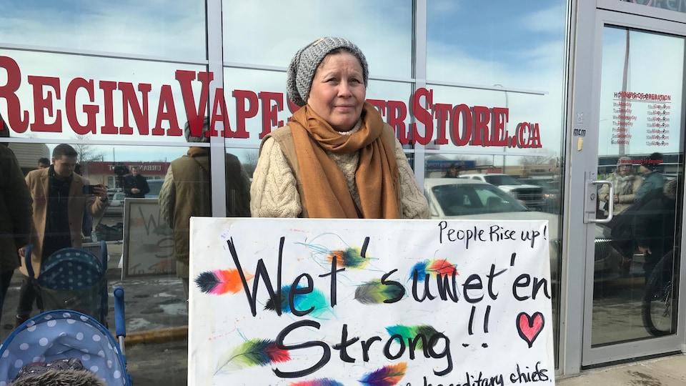Une manifestante tient une pancarte qui appuie les Wet'suwet'en devant le bureau de circonscription d'Andrew Scheer, le chef du Parti conservateur.