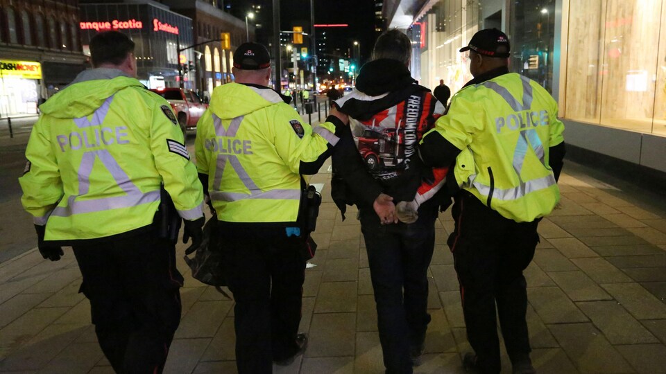 A demonstrator, from behind, handcuffed, was surrounded by police.