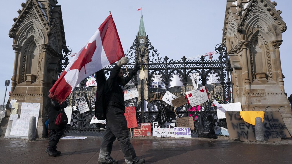 Un homme brandit un drapeau devant les grilles du parlement.