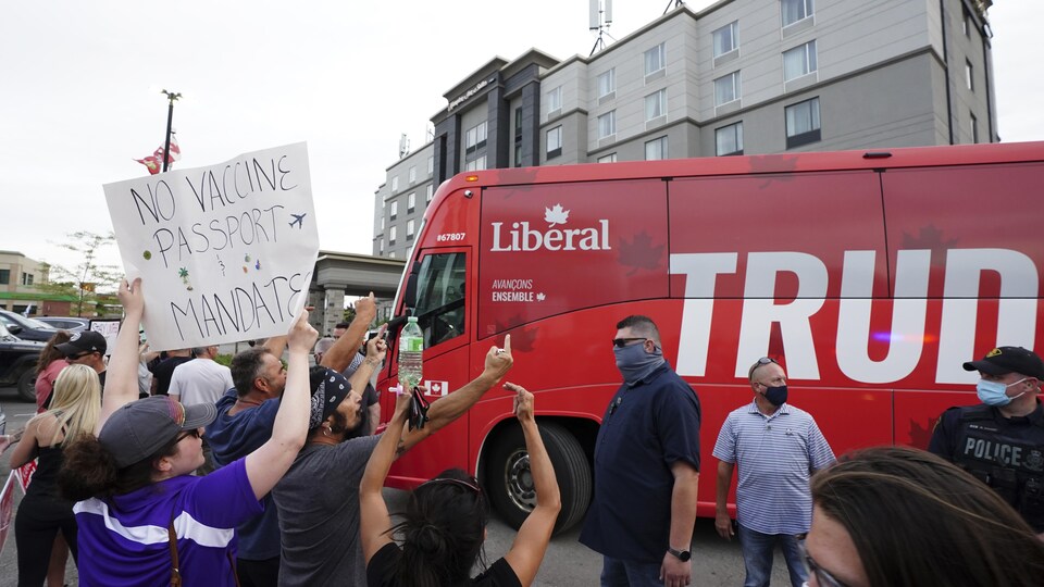 Une dizaine de personnes font des signes vulgaires à l'autobus de campagne du libéral Justin Trudeau.