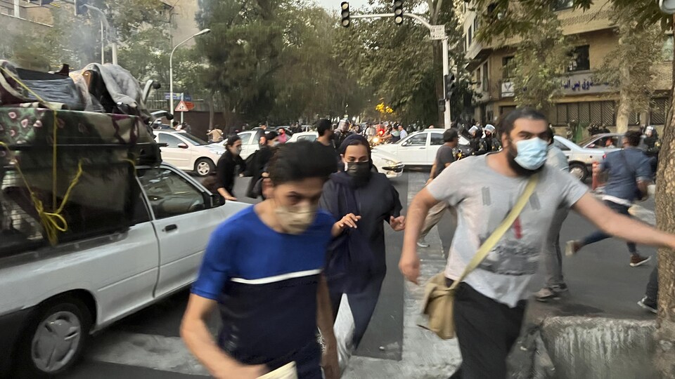 Des manifestants courent dans une rue de Téhéran.