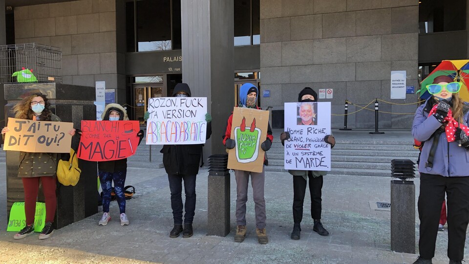 Des manifestantes brandissant des pancartes à l'entrée du palais de justice.