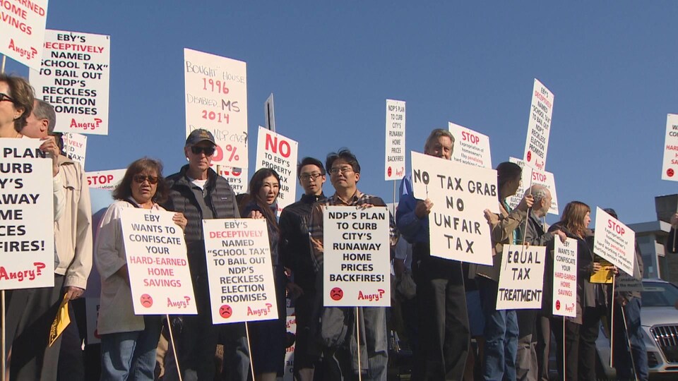 Des manifestants avec des pancartes dénonçant la hausse de taxe. 