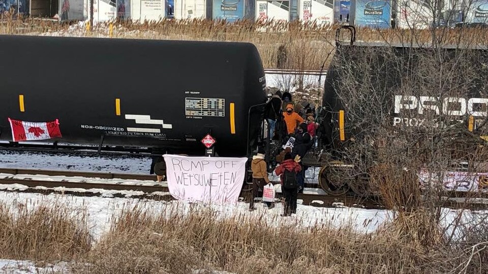 Des manifestants entre des wagons sur une voie ferrée.