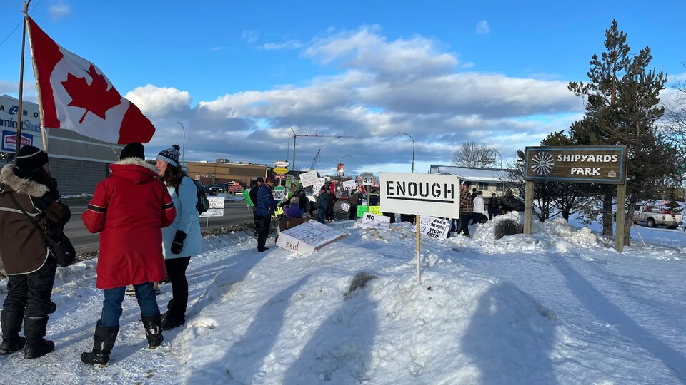 Une dizaine de manifestants sont au bord d'une route pour dénoncer les mesures de santé publiques lors d'un rassemblement à Whitehorse.