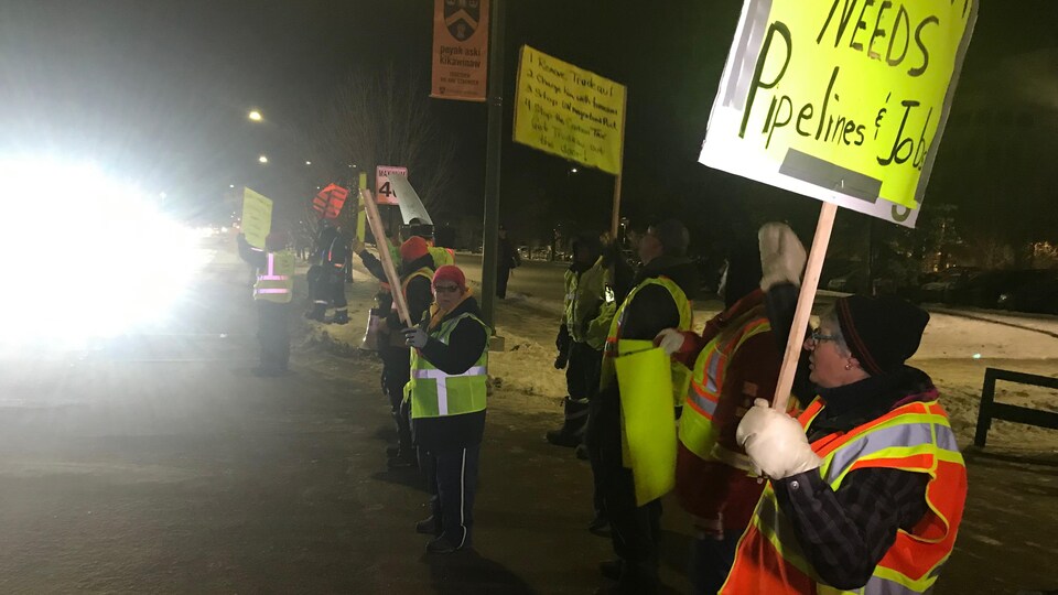 des manifestants  pancarte en main et portant des gilets jaunes.