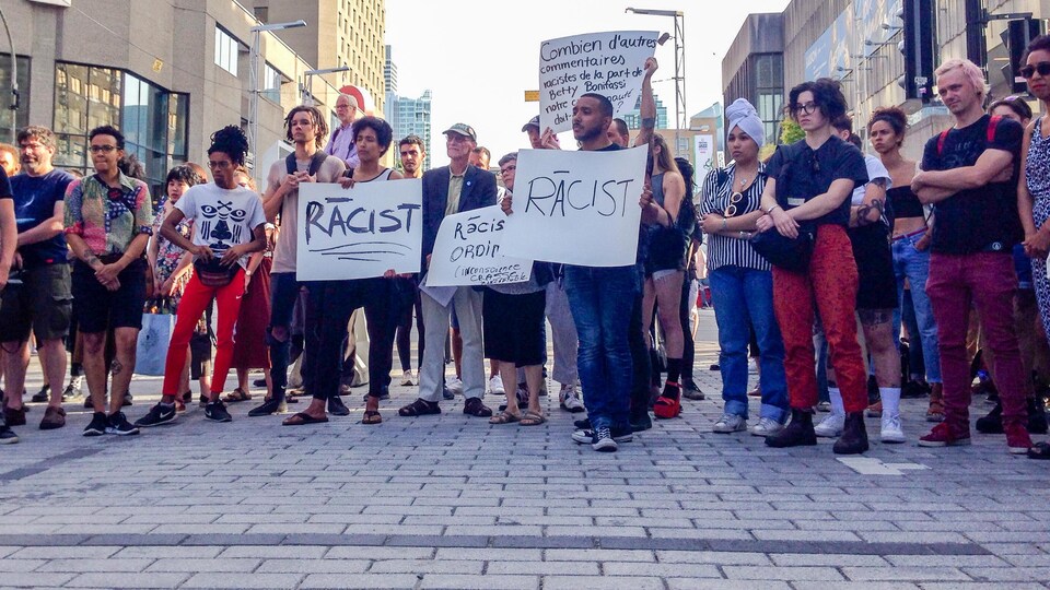 Des manifestants tiennent silencieusement des pancartes qui dénoncent le racisme derrière l'appropriation des chants d'esclaves par des artistes blancs, le 26 juin, durant une représentation du spectacle «SLAV».