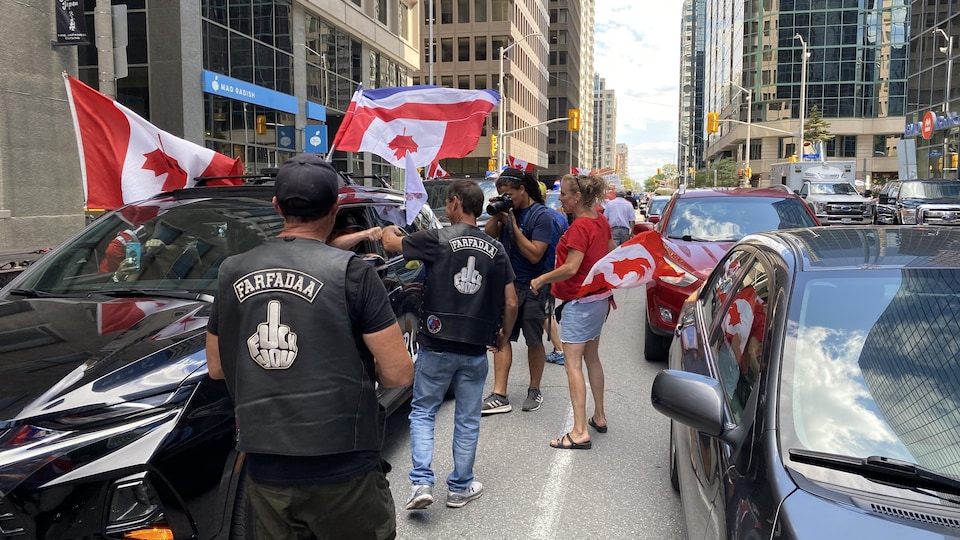 Des gens agitent des drapeaux dans les rue du centre-ville d'Ottawa.