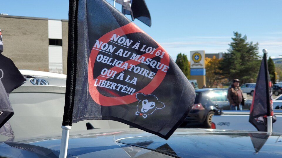 Drapeau sur lequel est écrit : Non à loi 61, non au masque obligatoire, oui à la liberté!!!