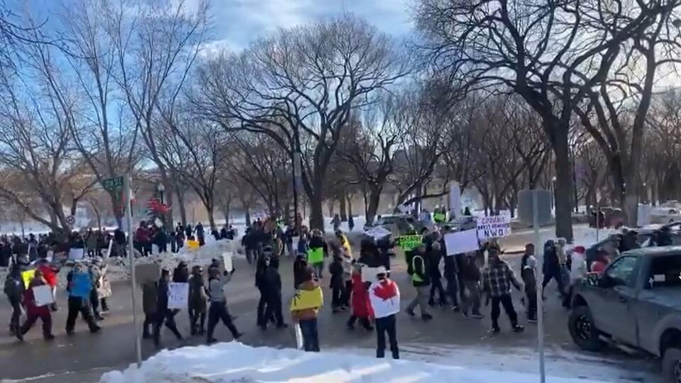 Plusieurs personnes manifestent dehors avec des pancartes à la main.