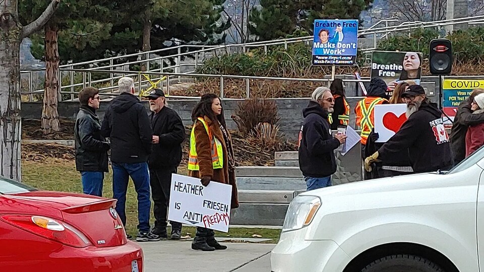 Des manifestants contre le port du masque sont debout sur un trottoir à Kelowna.