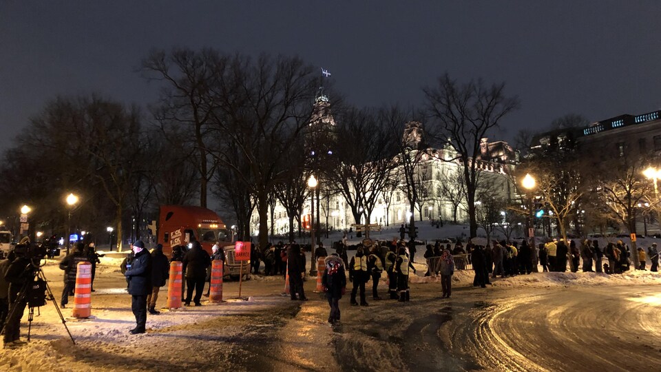 Des manifestants protestent contre les mesures sanitaires près du parlement de Québec, le soir, en hiver.